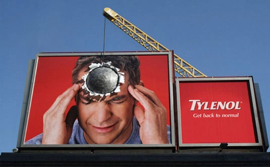 An image of a billboard advertisement for the painkiller Tylenol, wherein the feeling of a headache with a wrecking ball impacting a man's head.