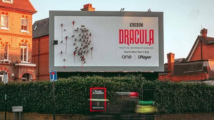 An Out of Home advertisement for the BBC show Dracula. At Daytime, the ad is comprised of actual wooden stakes stuck into the billboard itself with what appears to be blood dripping.
